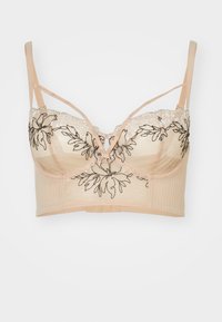 Spiss og mesh-bralette i nude med svart blomsterbroderi. Har justerbare stropper, frontlukking og en strukturert silhuett.