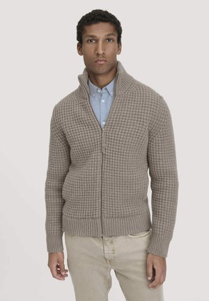 Beige gestrickter Reißverschluss-Pullover mit strukturiertem Muster, gerippten Bündchen und Saum. Wird über einem hellblauen Hemd mit Kragen getragen, das einen Stehkragen hat.