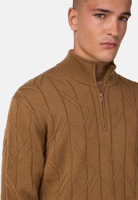 Brauner gestrickter Pullover mit hohem Kragen und Viertel-Reißverschluss. Verfügt über ein strukturiertes Blättermuster, gerippte Akzente und eine taillierte Passform.