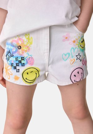 Shorts blancs avec des motifs colorés imprimés, y compris des visages souriants, des fleurs et des cœurs. Fabriqués en denim avec une coupe décontractée.