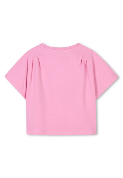 T-shirt à manches courtes, col rond en coton rose clair. Présente des plis aux épaules et un ourlet droit et court. Texture douce.