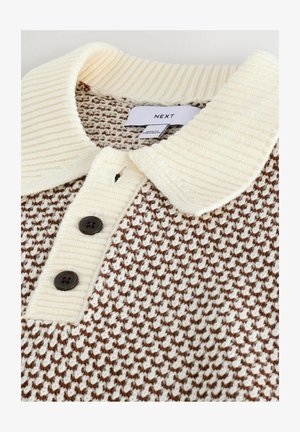 Pulover tricotat cu guler crem, cu nervuri și un model geometric maroniu. Are trei nasturi închiși la culoare la gât și o etichetă.