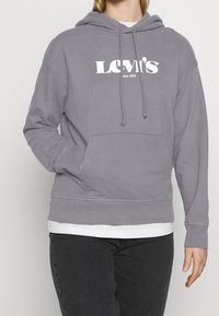 Felpa grigia in cotone con tasca frontale, cappuccio con lacci, polsini a coste e logo bianco "Levi's" stampato sul petto.