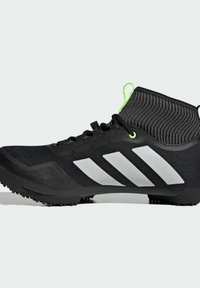 Chaussure de sport noire avec un col en tricot texturé, trois rayures blanches et une boucle d'accent vert, dotée d'une semelle moulée pour une meilleure adhérence.