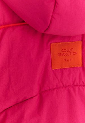 Różowa pikowana kurtka z pomarańczową metką z wytłoczonym napisem "COLOR REVOLUTION". Materiał wydaje się lekki o gładkiej fakturze.