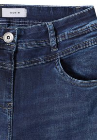Donkerblauwe denimjeans met een knoopsluiting, riemlussen en een voorzak. Heeft contrasterende stiksels en een gladde, licht getextureerde afwerking.