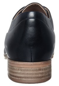 Chaussure en cuir noir avec une forme arrondie et un talon bas empilé. Surface texturée et accents de talon marron clair contrastants.