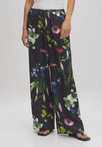 Brede broekspijpen van lichtgewicht stof met een levendig bloemenpatroon op een zwarte achtergrond en een elastische tailleband.