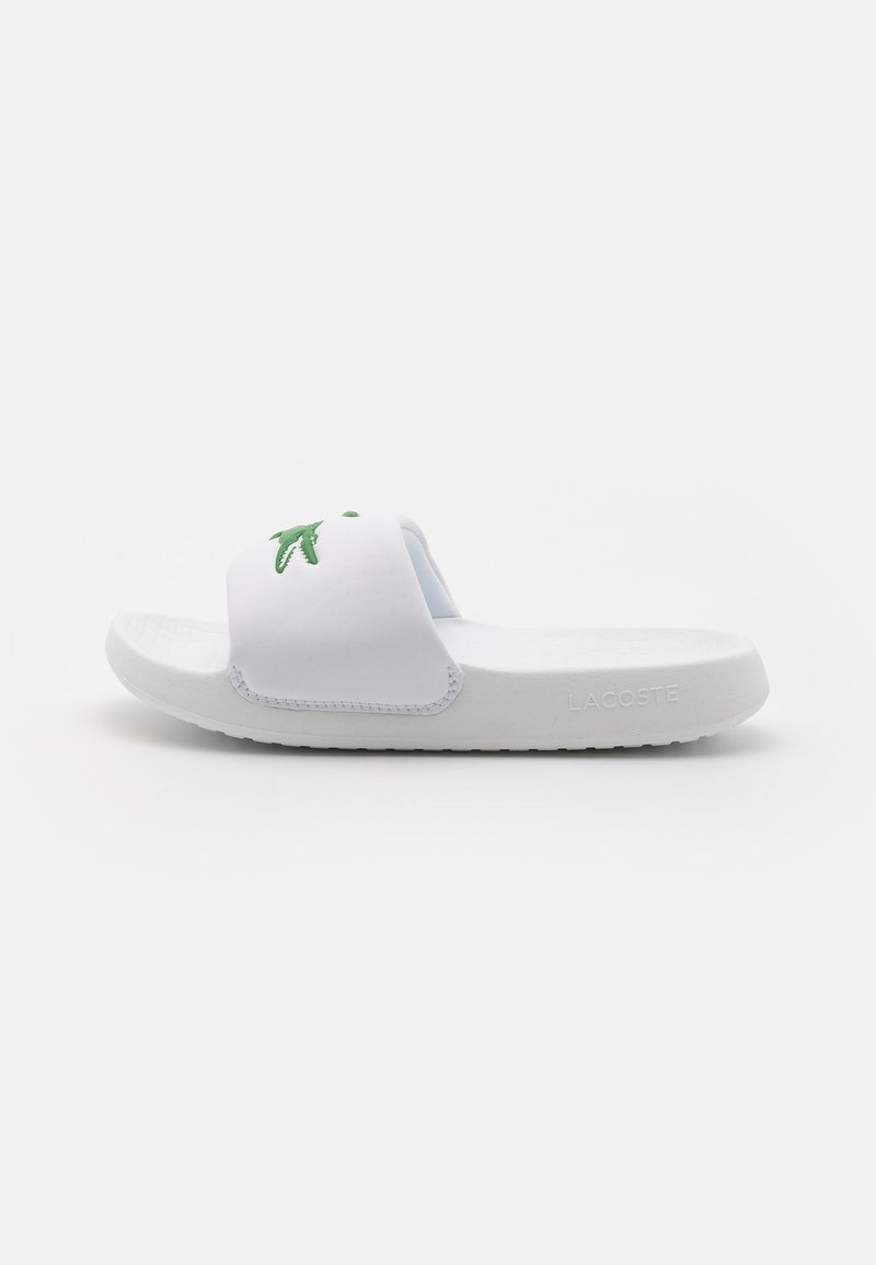 Sandale blanche à glissière en matériau synthétique, arborant un logo crocodile vert sur la bride et une semelle texturée pour une meilleure adhérence.