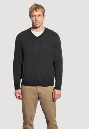 Dunkelgrauer V-Ausschnitt-Pullover aus Strickstoff, mit langen Ärmeln sowie gerippten Bündchen und Saum, getragen zu hellbeigen Hosen.
