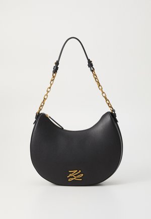 Black leather shoulder bag with a curved shape, gold hardware accents, and a chain strap. Features a zip closure and branded logo detail.