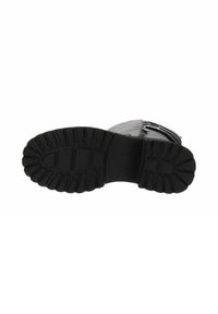Suela de zapato de goma negra con surcos profundos, textura suave y forma redondeada. Presenta un logotipo en relieve y un talón reforzado para mayor durabilidad.