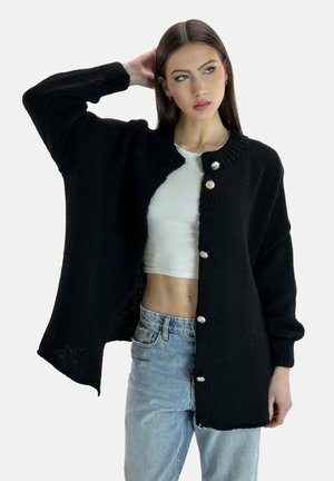 Zwarte gebreide cardigan met een ronde kraag, gouden knopen en oversized mouwen, voorzien van een textuurpatroon en een open voorkant.