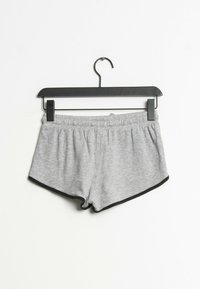 Šedé bavlněné šortky s černým lemem, mají elastický pás a boční sklady, vystavené na černém ramínku na bílém pozadí.