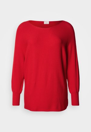 Punainen ribbineulottu neulepaita pyöreällä pääntiellä, pitkillä hihoilla ja leveillä kalvosimilla. Vyötäröllä väljyyttä ja koko vaatteen läpi hienovarainen tekstuuri.