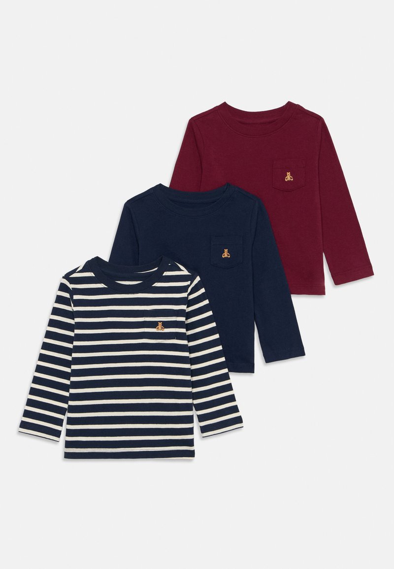 Tre langermede skjorter i marineblå, burgunder og marineblå stripe. Hver av dem har en liten lomme med en brun brodert logo.