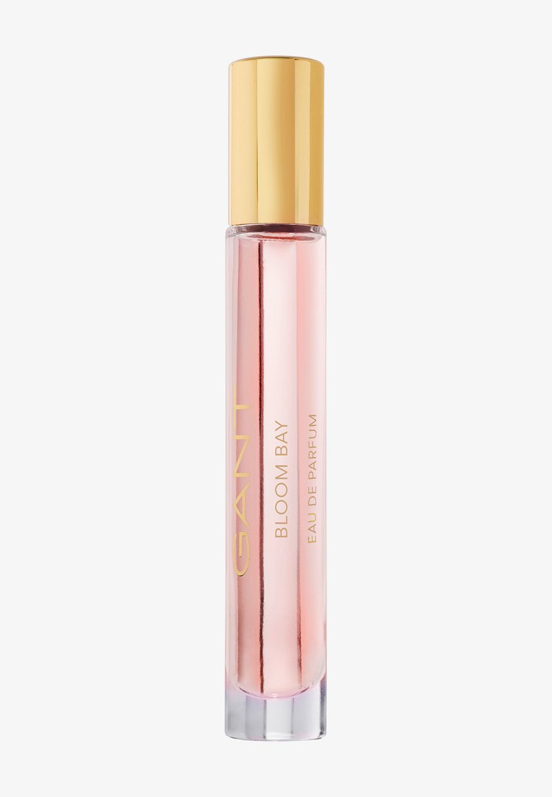 Flacon de parfum mince transparent rose avec un bouchon doré étiqueté GANT Bloom Bay Eau de Parfum.
