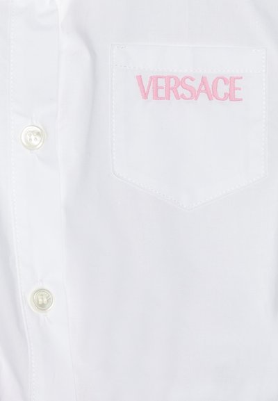 Hvit skjorte med knapper som har en rosa brodert "VERSACE"-logo på venstre brystlomme. Glatt stoff med klassisk kragedesign.