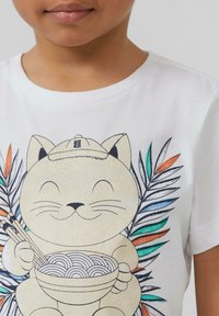 Witte katoenen T-shirt met een cartoonkat die een kom noedels vasthoudt, omringd door groene en oranje bladeren. Zachte textuur.