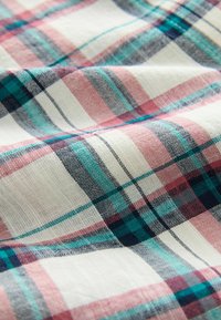 Katoenen stof met een veelkleurig ruitpatroon met rode, blauwe en witte lijnen. Zachte textuur met zichtbare weefdetails.