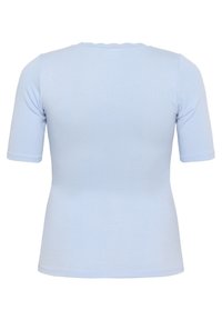 T-shirt côtelé bleu clair avec des manches courtes et un col en scallop. Texture lisse, design ajusté et lignes simples et épurées.