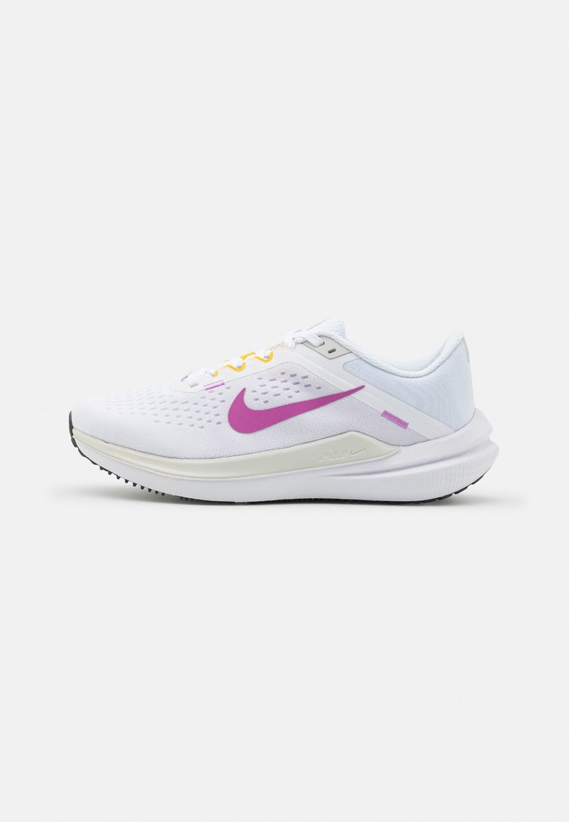 Zapatillas de running Nike con parte superior de malla blanca, swoosh púrpura, acentos amarillos y púrpuras, y una suela exterior de goma negra texturizada.