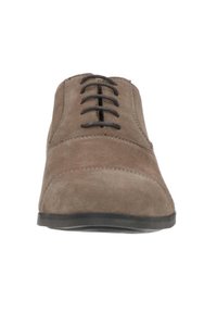 Bruine nubuck veterschoen met een ronde neus, voorzien van zwarte veters en een dunne rubberen zool. Gekreukt bovenwerk met subtiele stikdetails.