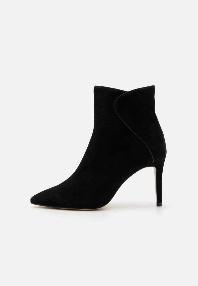 Bottine en daim noir avec un bout pointu et un design épuré. Présente un talon aiguille haut et une coupe asymétrique en haut.
