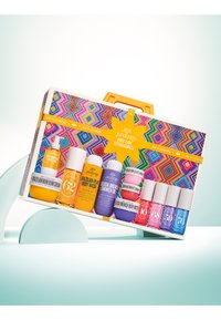 Kroppsvårdsett i en färgglad, mönstrad låda med ett orange handtag, som innehåller olika lotioner och oljor i färgglada flaskor med etiketter.