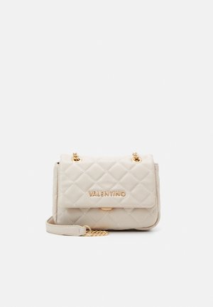 Beige gesteppte Handtasche mit goldenen Beschlägen, ausgestattet mit einem Klappverschluss und einer Kettenriemen. Das Design umfasst ein Logo auf der Vorderseite.