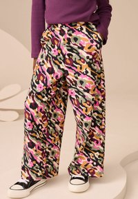 Lockere Hose mit mehrfarbigem Leopardenmuster in Rosa, Grün und Orange. Aus weichem Stoff mit seitlichen Taschen gefertigt.