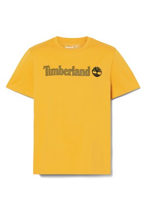 Maglietta in cotone gialla con la scritta "Timberland" in testo marrone scuro e un piccolo logo ad albero sul lato sinistro. Design classico con scollo rotondo.