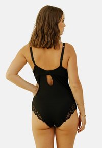 Bodysuit noir avec bord en dentelle, dos en clé, bretelles ajustables et texture lisse. Conçu pour une silhouette ajustée.