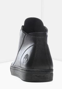 Czarne skórzane botki za kostkę o gładkim wykończeniu, zaokrąglonym nosku i gumowej podeszwie. Posiadają wytłoczone logo Timberland po boku.