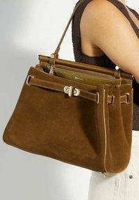 Brown suede handbag with a structured design, featuring a gold-tone hardware clasp, dual handles, and an inner zippered pocket.