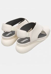 Sandali bianchi in pelle con design incrociato, cinturino elastico sul tallone e una suola in gomma spessa e arrotondata. Soletta grigia con logo del marchio.