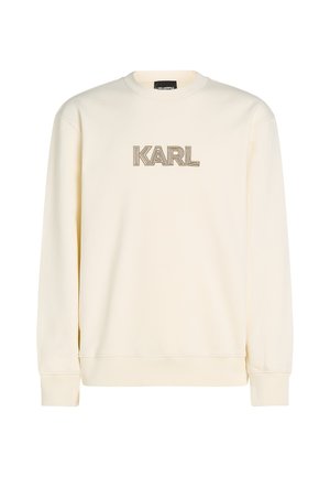 Cremefarvet sweatshirt med rund hals og lange ærmer. Har ordet "KARL" i en gylden, dekorativ skrifttype på fronten.