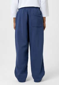 Marineblauwe sweatpants met een elastische tailleband, voorzien van een enkele achterzak en een relaxte pasvorm. Gemaakt van een zachte, gestructureerde stof.