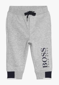 Šedé bavlněné joggery s elastickým pasem a námořnickým stahovací šňůrkou. Na levé noze mají potisk loga a námořnické žebrované manžety.