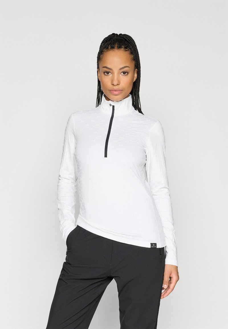 Top alb cu mâneci lungi și fermoar, cu guler înalt, design texturat și fermoar negru. Asortat cu pantaloni negri.