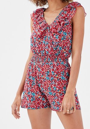 Combinaison sans manches à motif floral rouge, bleu et blanc, col en V froncé et taille élastique portée par une personne debout.