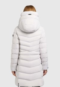 White puffer coat featuring a chevron quilting pattern, a high collar, and a hood. Soft texture with black hardware detailing on sleeves.