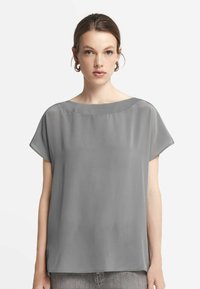 Grå kortärmad blus med vid halsringning och lös passform. Slät, lättviktig tyg med en subtil glans. Minimalistisk design utan mönster.