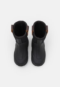 Bottes étanches noires avec semelles en caoutchouc. Design élégant, tige en tissu et accents en cuir marron au talon. Style minimaliste, construction robuste.