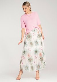 Jasnoróżowy, puszysty sweter z dzianiny w połączeniu z zwiewną, plisowaną spódnicą maxi w kwiaty w delikatnych odcieniach. Zestaw zawiera przejrzyste sandały na blokowym obcasie.