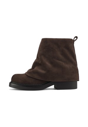 Stivali alla caviglia in suede marrone con un design drappeggiato, punta tonda e tacco basso nero; include un tab di estrazione sul retro per facilitare la calzata.