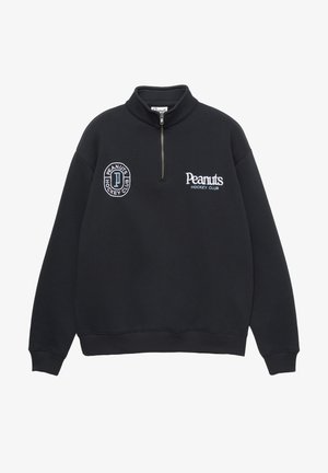 Sort lynlåstrøje med høj krave, med broderet "Peanuts Hockey Club" logo og cirkulært mærke på venstre bryst. Blødt materiale.