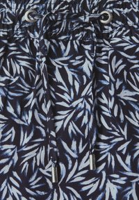 Shorts navy avec un motif de feuilles blanches, fabriqués en tissu doux. Ils possèdent une taille élastique avec un cordon de serrage et des embouts en métal.