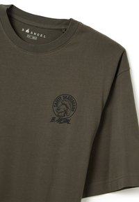 Camiseta de algodón verde oliva con mangas cortas, presenta un escote redondo y un estampado gráfico negro en el lado izquierdo del pecho que representa a un personaje.