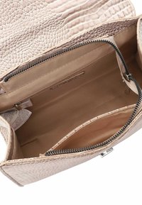 Gevoerde interieur van een roze fauxleren handtas met crème lining, voorzien van een ritscompartiment en twee open zakken voor organisatie.
